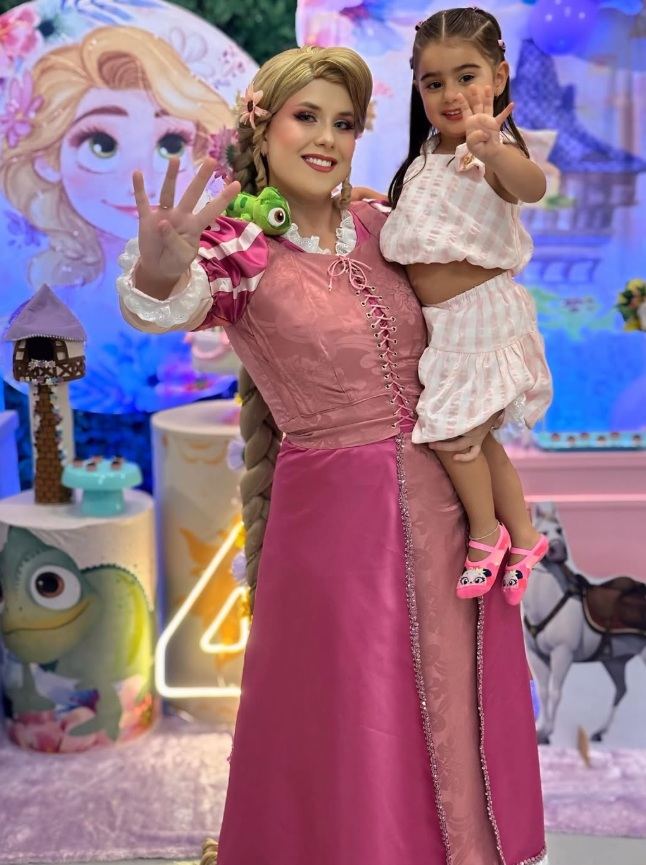 Rapunzel segurando a aniversariante no colo em festa infantil com tema Enrolados